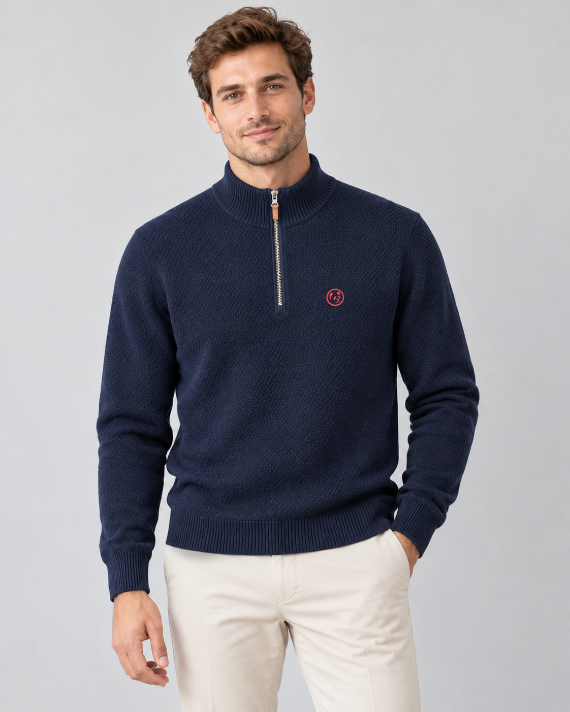 Modelo con jersey azul marino de LaPanda, cuello alto con media cremallera y panda bordado rojo coral, combinado con pantalones crudos